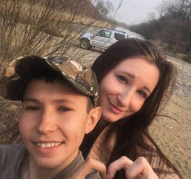 Pareja joven tomándose una selfie al aire libre formando un corazón con las manos.