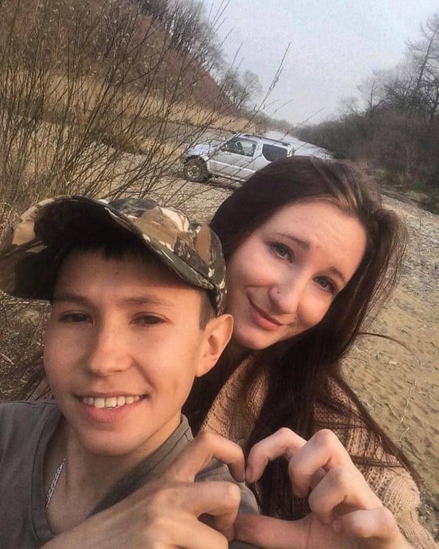 Pareja joven tomándose una selfie al aire libre formando un corazón con las manos.