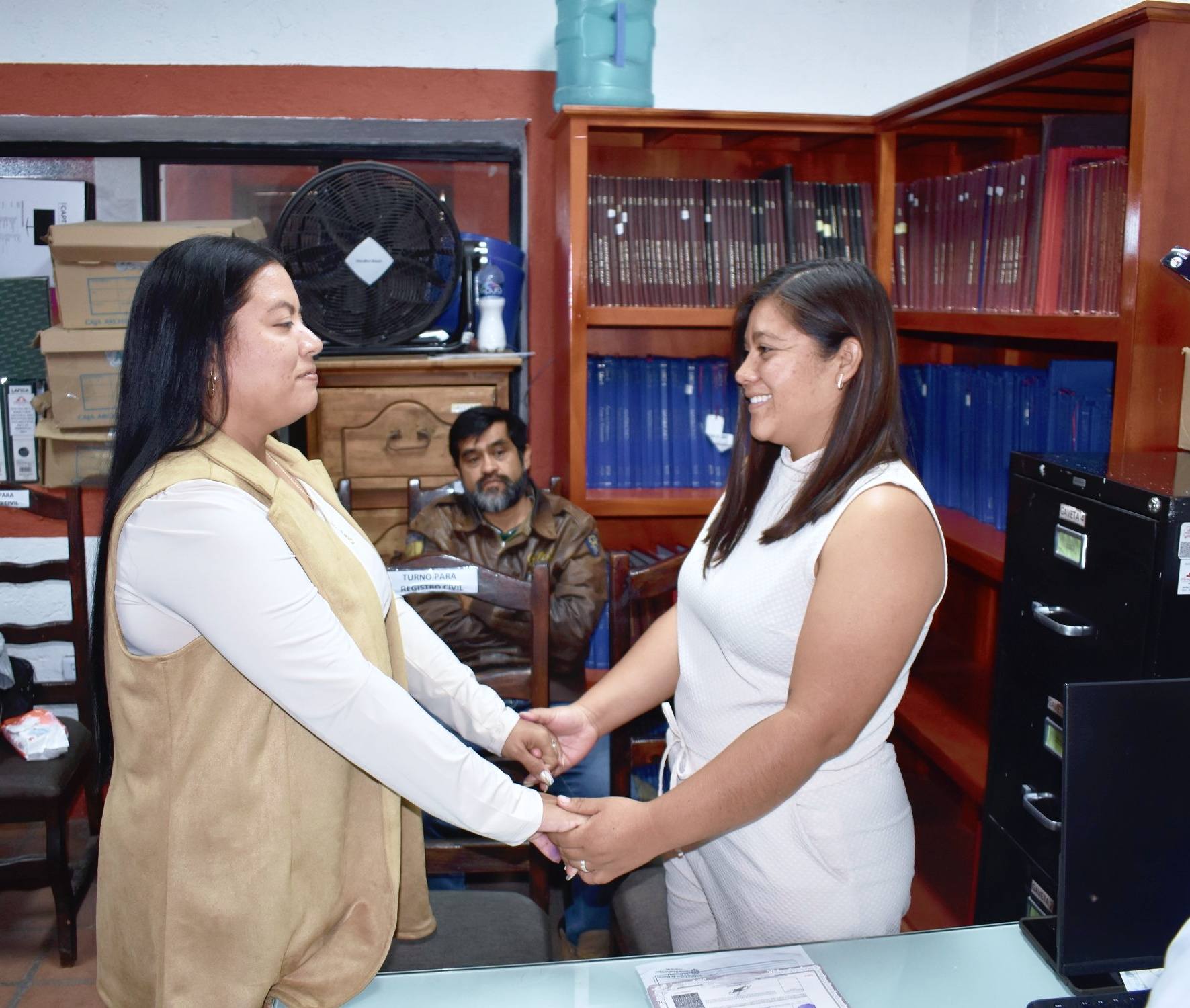 Dos mujeres tomadas de las manos durante su ceremonia de matrimonio civil en una oficina del Registro Civil de Huaquechula.