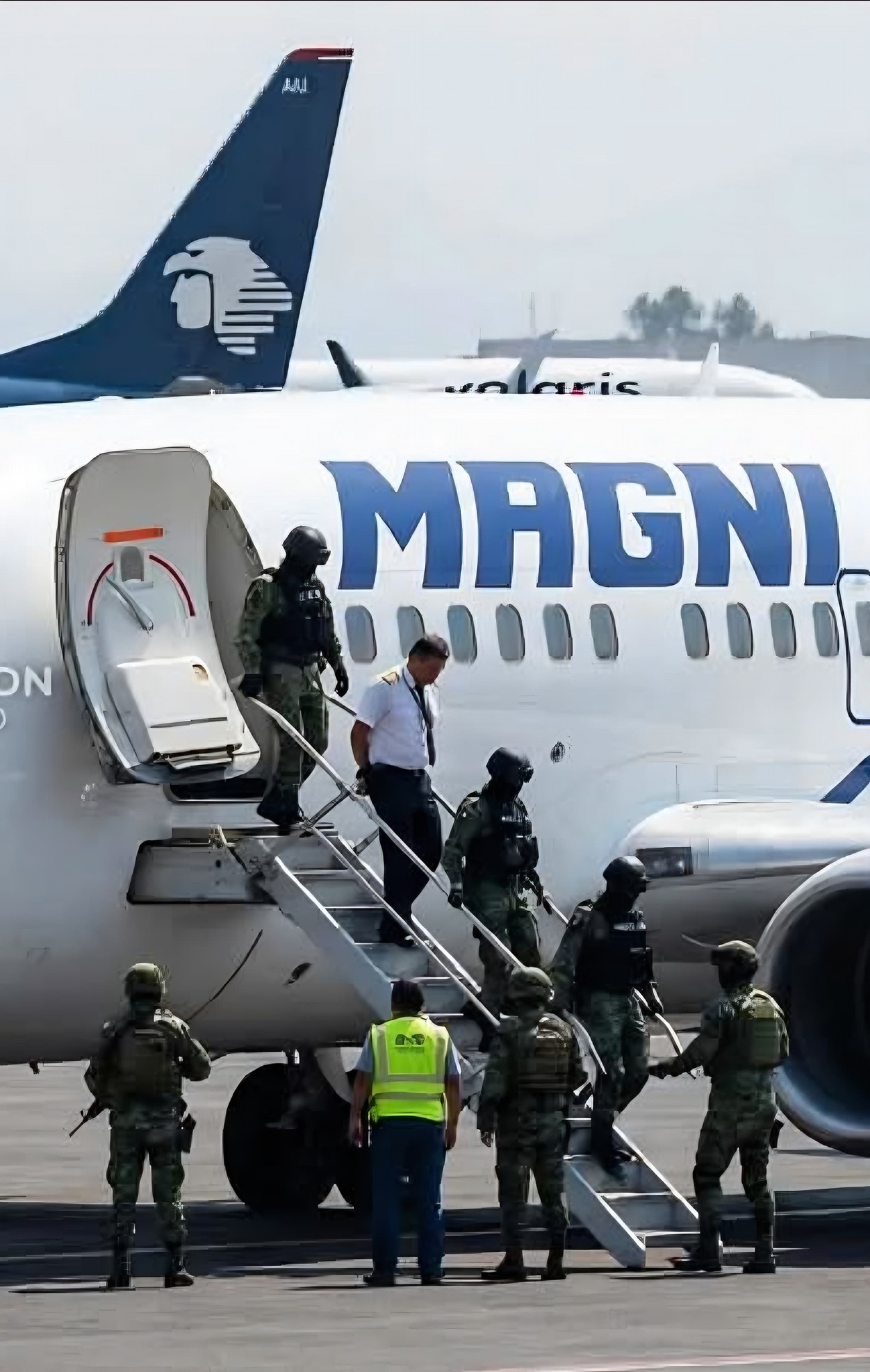 Elementos de seguridad escoltan a una persona fuera de un avión en el Aeropuerto Internacional de la Ciudad de México.