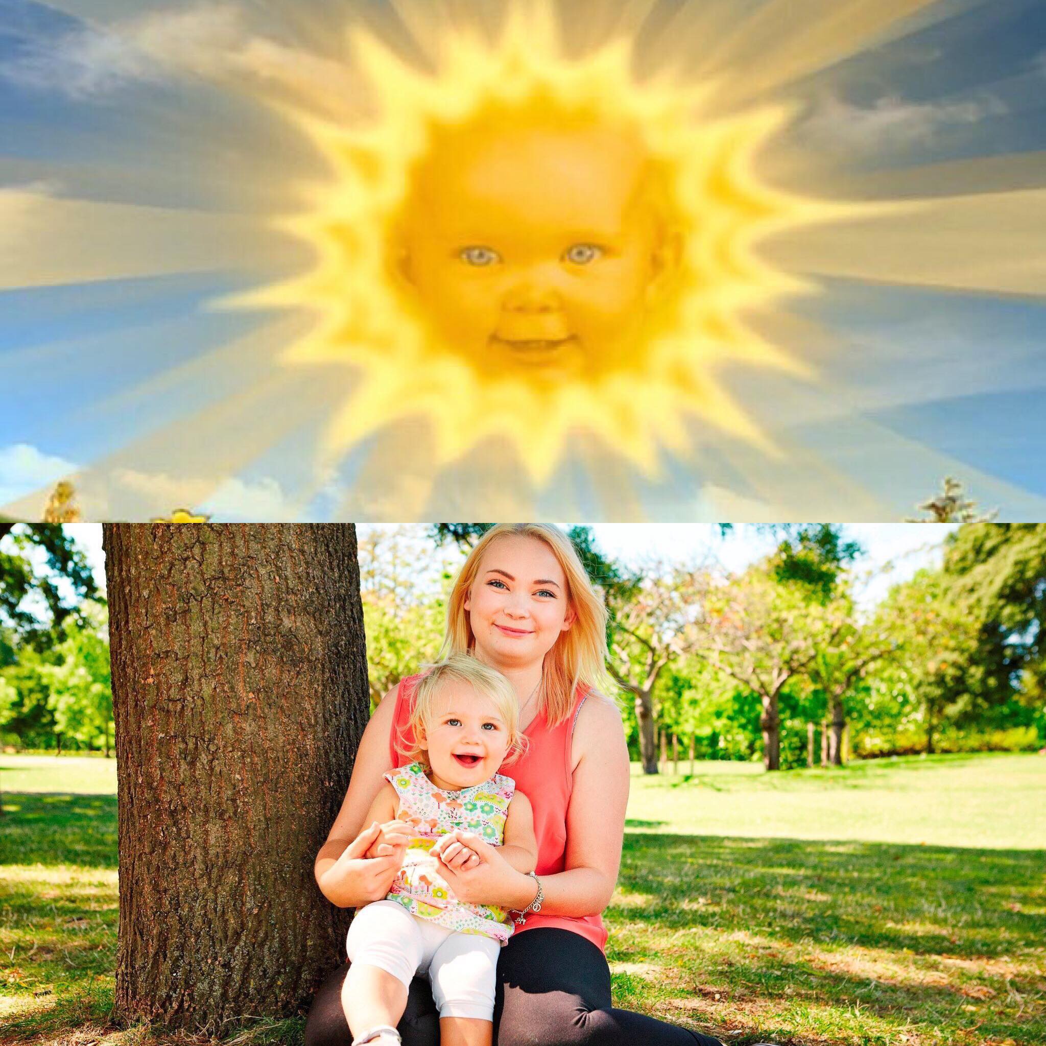 Montaje con el antiguo sol de un programa infantil con cara de bebé en el cielo y, debajo, una mujer joven sentada en el pasto abrazando a su hija pequeña en un parque.