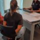 Pareja sentada frente a una oficial en una oficina realizando un trámite o proceso legal, conversando sobre documentos judiciales.