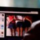 Persona frente a una computadora con contenido borroso que sugiere imágenes inapropiadas, representando el riesgo de explotación infantil en línea.