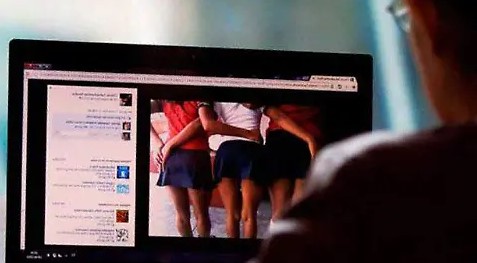 Persona frente a una computadora con contenido borroso que sugiere imágenes inapropiadas, representando el riesgo de explotación infantil en línea.