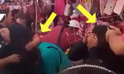 Comerciantes someten a dos mujeres acusadas de robo en un mercado, mientras varias personas observan y señalan la escena.