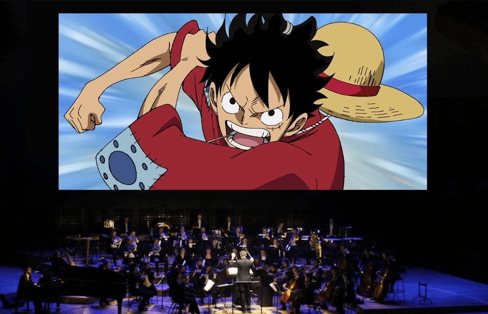 Escena de One Piece proyectada sobre escenario de una orquesta sinfónica durante un concierto.