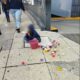 Menor sentado en la banqueta de una avenida de la Ciudad de México con un bote de gelatinas para venta.