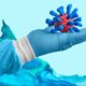 Representación del virus de la influenza sostenido por una mano con guante médico.