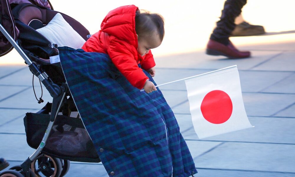 Bebé en Japón sosteniendo una bandera nacional, símbolo de la crisis de natalidad del país.
