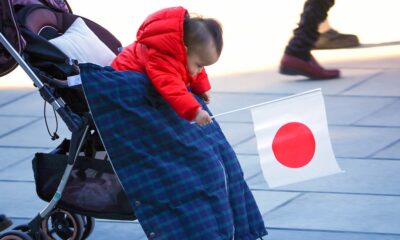 Bebé en Japón sosteniendo una bandera nacional, símbolo de la crisis de natalidad del país.