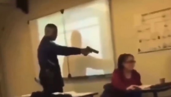 Estudiante amenaza a docente con un arma dentro de un salón de clases mientras otros observan.