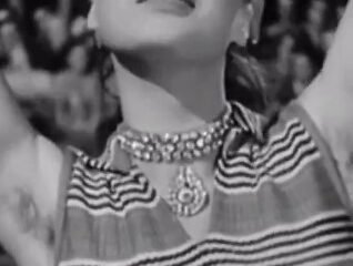 Mujer con actitud seductora levantando los brazos en una escena clásica en blanco y negro.x