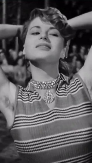 Mujer con actitud seductora levantando los brazos en una escena clásica en blanco y negro.x