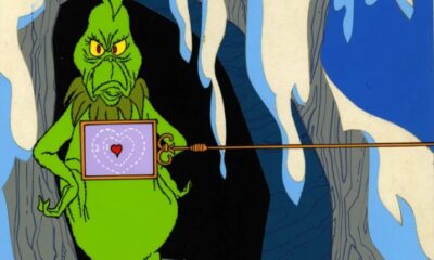 Ilustración del Grinch con expresión de disgusto frente a una cueva nevada.