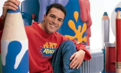 Presentador Rui Torres de Art Attack sonriendo en un set colorido con lápices gigantes.