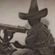 Soldado revolucionario operando una ametralladora, posiblemente durante la Revolución Mexicana.