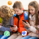 Niños utilizando teléfonos y tabletas mientras interactúan con íconos de redes sociales, representando el uso digital temprano.