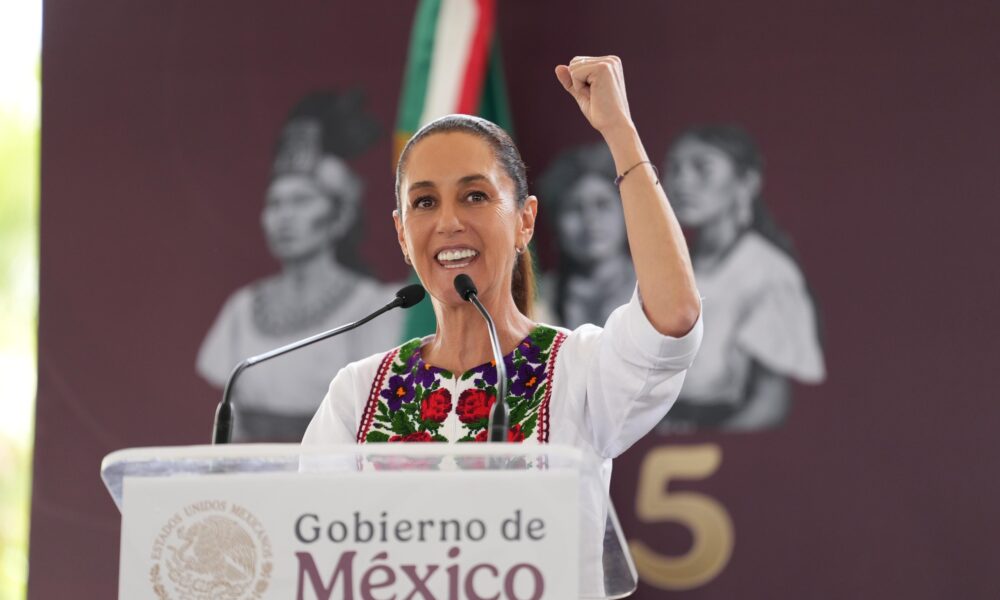 Claudia Sheinbaum hablando en un podio del Gobierno de México levantando el puño.