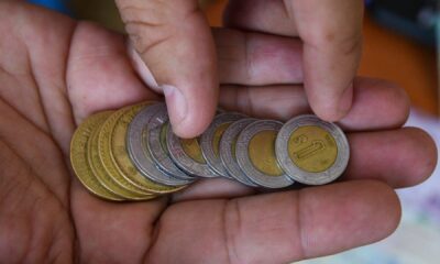 Mano contando monedas mexicanas de $1, $2, $5 y $10 pesos, representando el cambio monetario en México.