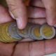Mano contando monedas mexicanas de $1, $2, $5 y $10 pesos, representando el cambio monetario en México.