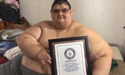 Juan Pedro Franco, ex hombre más obeso del mundo, sostiene un certificado Guinness mientras está sentado en una cama.