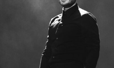 “José Madero cantando en concierto, vestido de negro y sosteniendo un micrófono, durante su presentación en un estadio iluminado.”