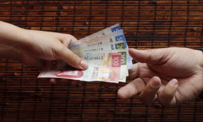 Intercambio de dinero en efectivo que representa el debate sobre el salario mínimo en México.