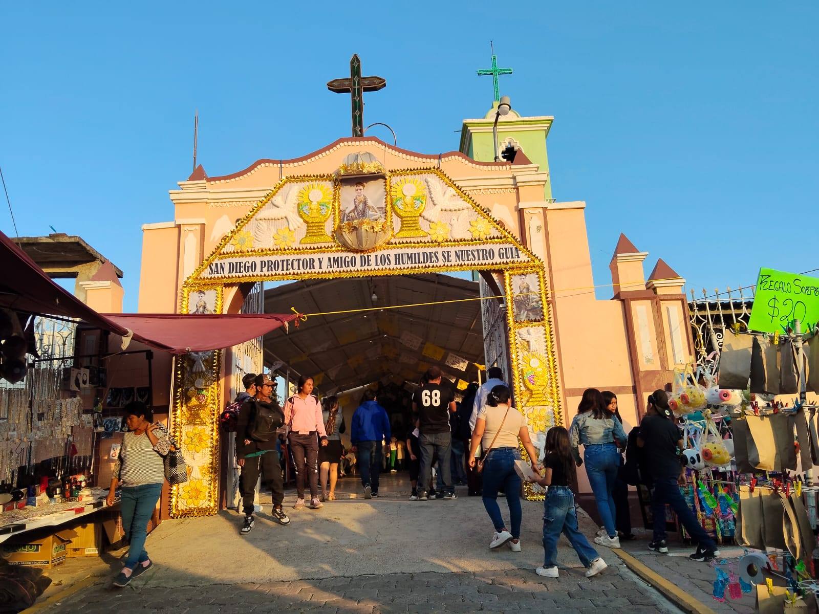 Entrada decorada del templo de San Diego el Organal durante la fiesta patronal en Huaquechula, con visitantes y puestos tradicionales.