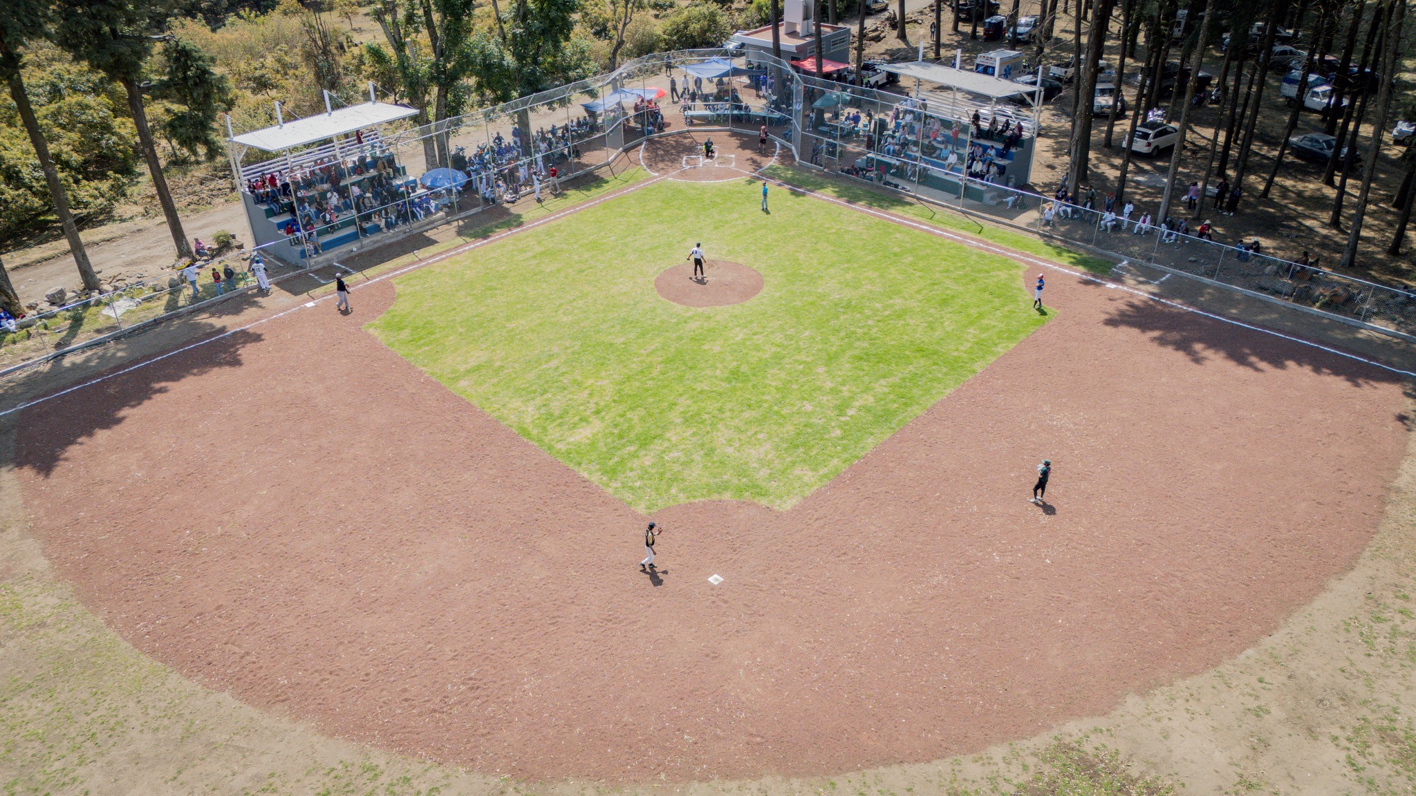 Campo de béisbol con gradas y público durante encuentro deportivo en Santa Catarina Cuilotepec, obra inaugurada por el Ayuntamiento de Tochimilco.