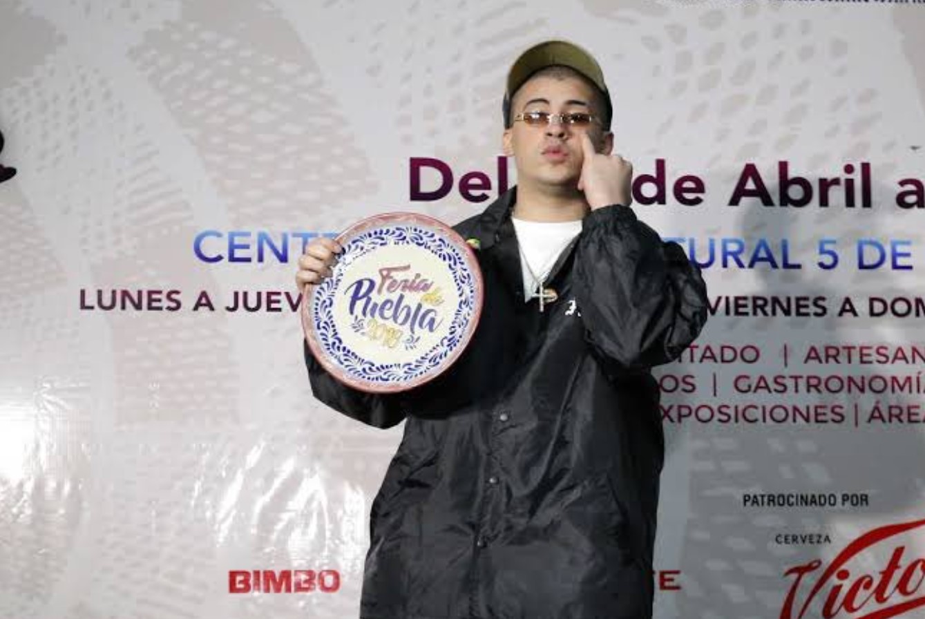 Bad Bunny sosteniendo un reconocimiento de la Feria de Puebla durante su visita al evento.