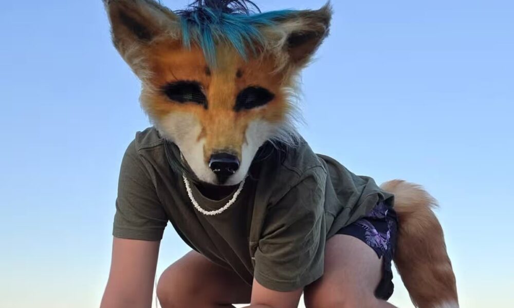 Persona usando una máscara de animal en un entorno al aire libre, relacionada con la conversación sobre la identidad therian.