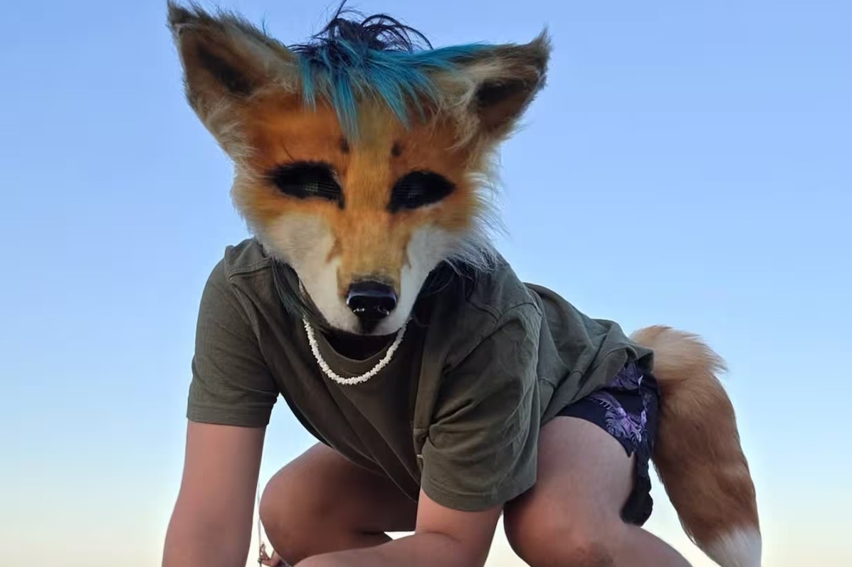 Persona usando una máscara de animal en un entorno al aire libre, relacionada con la conversación sobre la identidad therian.