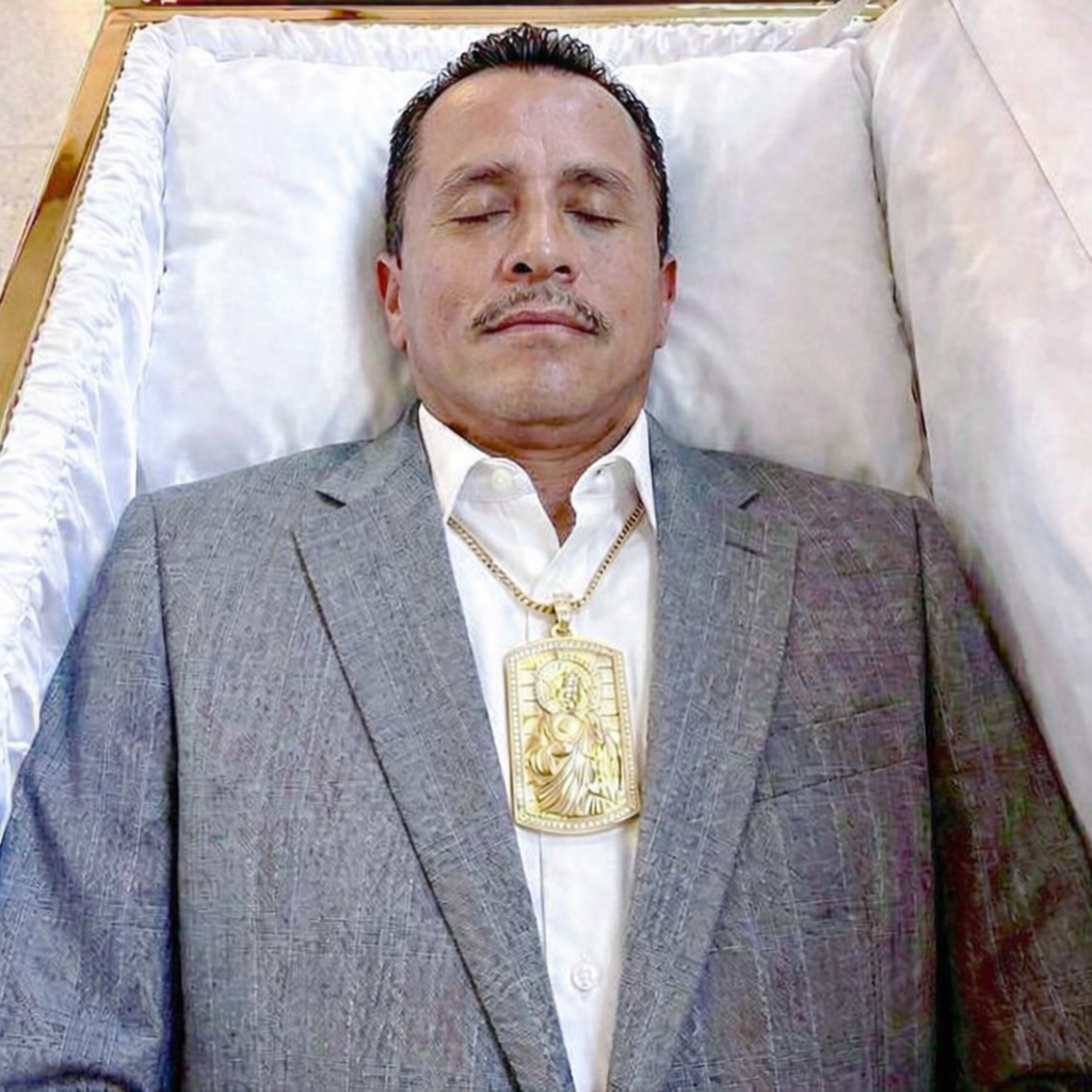 Fotografía viral de hombre dentro de un ataúd con traje y medallón dorado asociada a rumores sobre líder del narcotráfico en México.