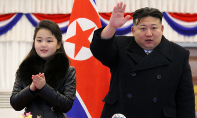 Líder de Corea del Norte acompañado de una menor en evento oficial frente a bandera nacional.