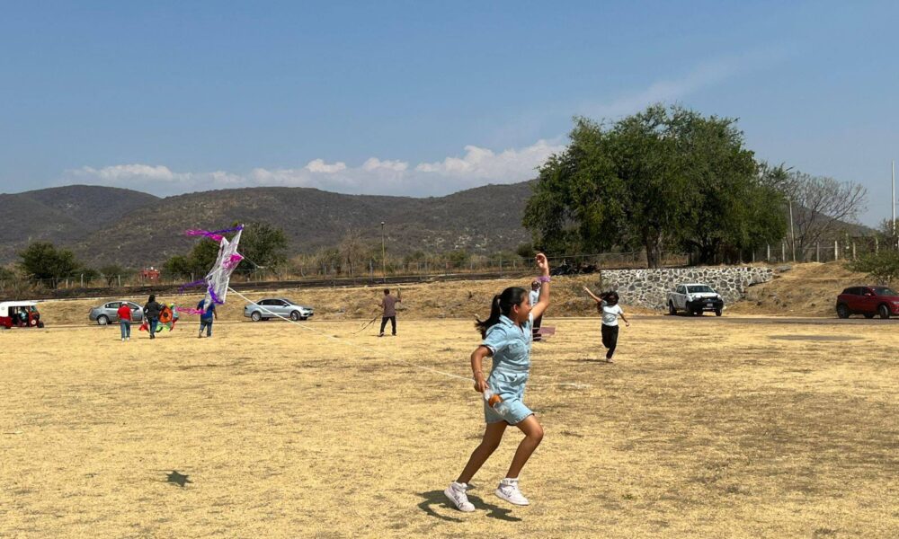 Niños participando en concurso de papalotes en Huaquechula Puebla con cometas volando en campo abierto