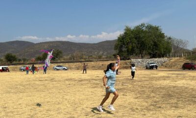 Niños participando en concurso de papalotes en Huaquechula Puebla con cometas volando en campo abierto