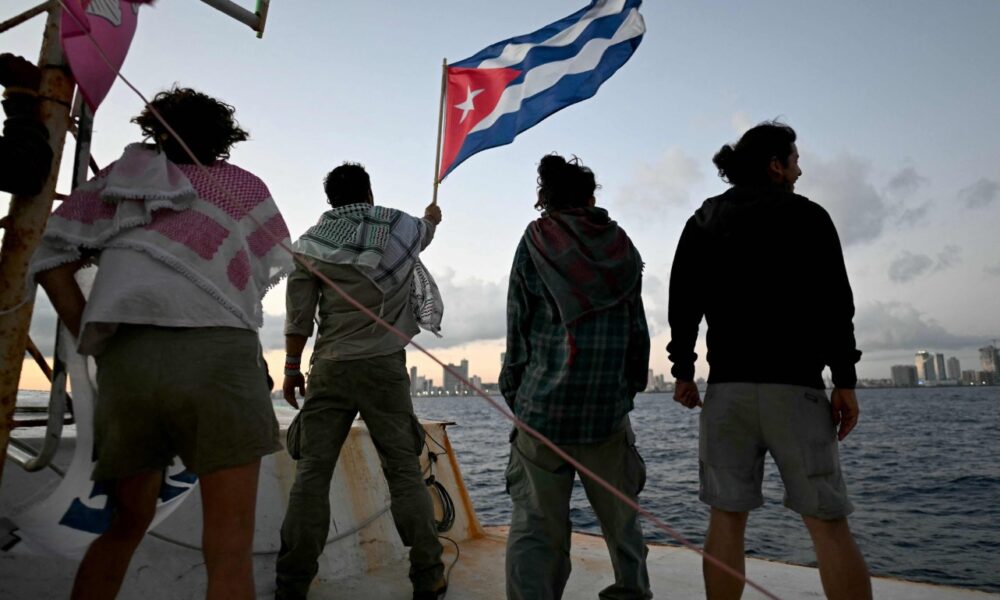 Personas sostienen bandera de Cuba en embarcación durante envío de ayuda humanitaria desde México