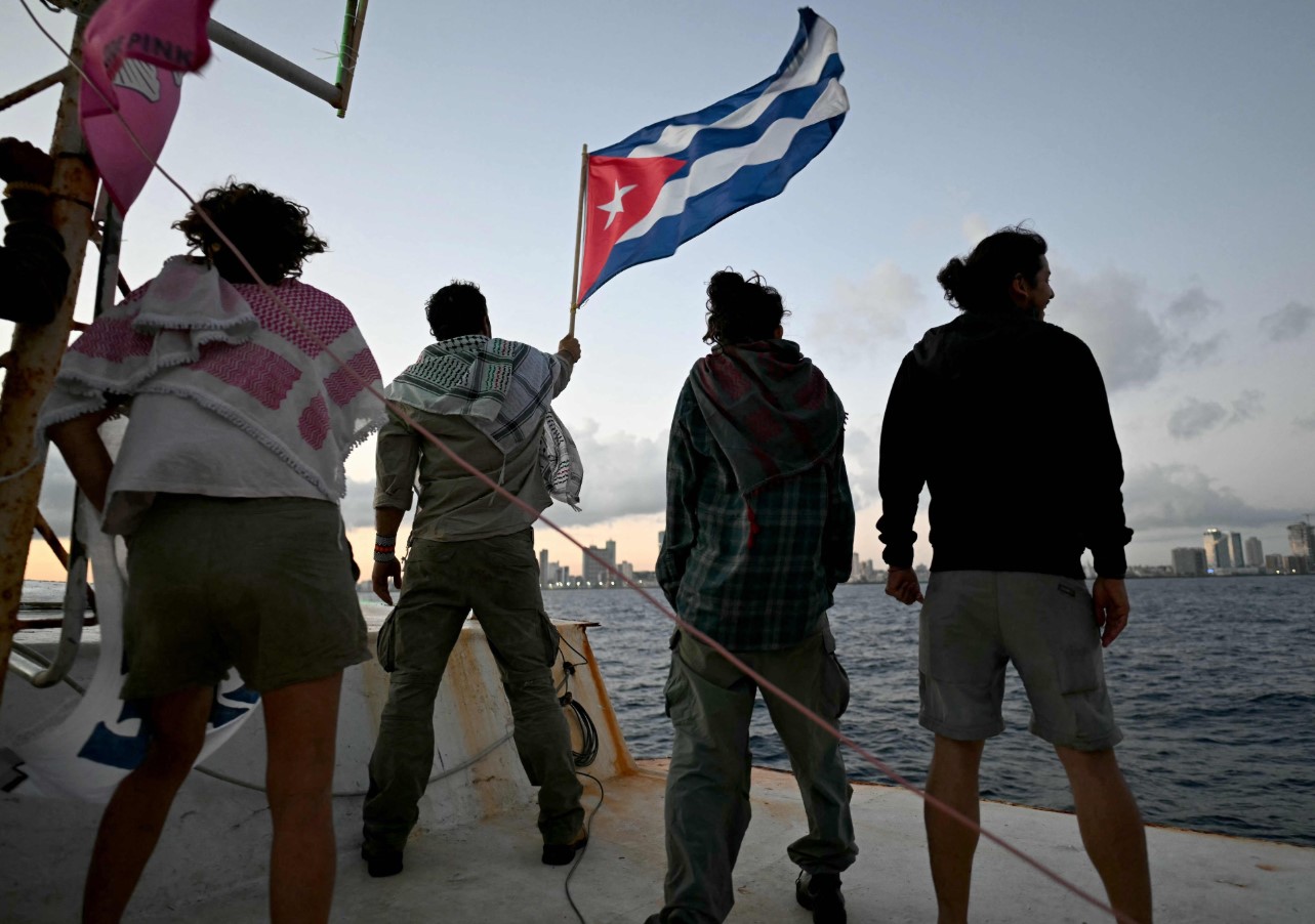 Personas sostienen bandera de Cuba en embarcación durante envío de ayuda humanitaria desde México