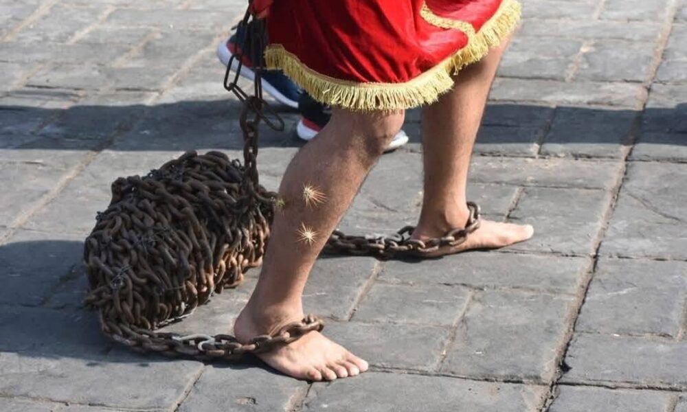 Hombre participante en tradición de engrillados en Huaquechula caminando con cadenas en los pies durante Semana Santa