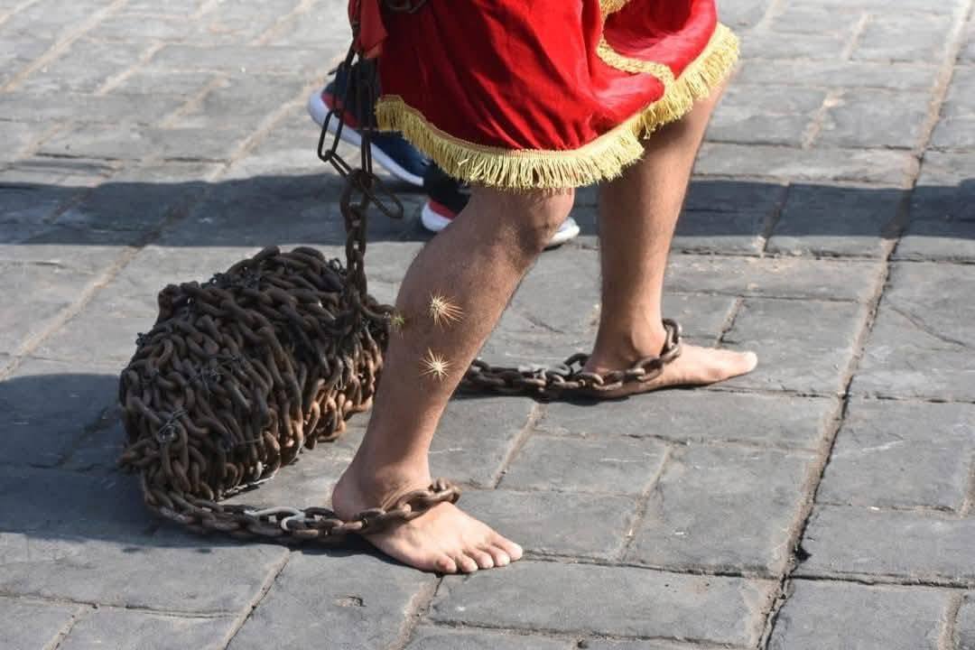 Hombre participante en tradición de engrillados en Huaquechula caminando con cadenas en los pies durante Semana Santa