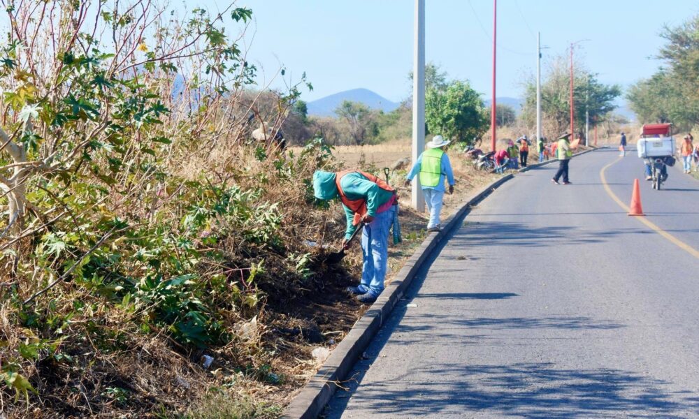 Trabajadores limpiando cunetas en carretera Huaquechula retirando basura para prevenir inundaciones