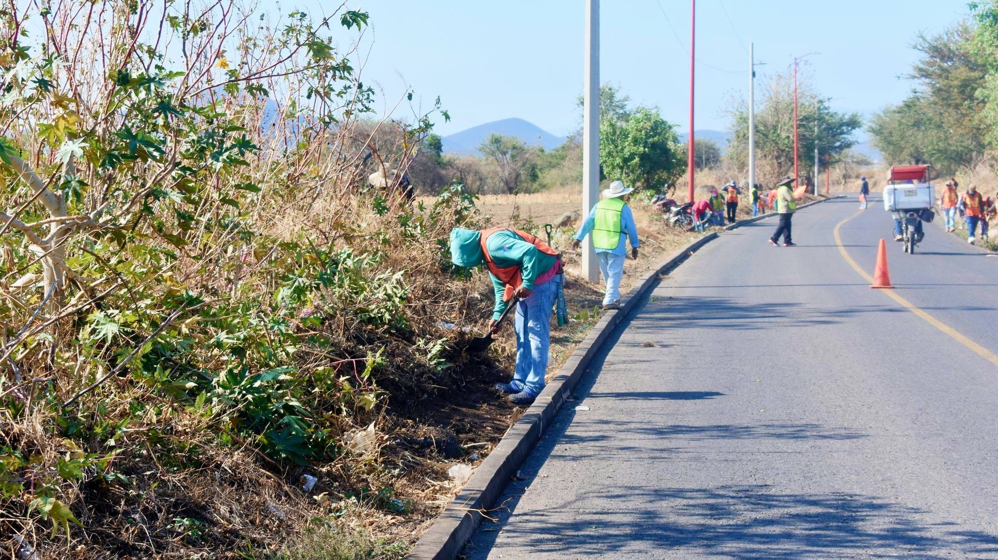 Trabajadores limpiando cunetas en carretera Huaquechula retirando basura para prevenir inundaciones