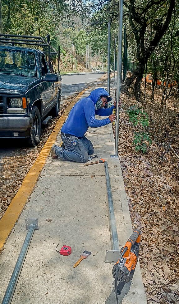 Trabajador instalando malla ciclónica en vialidad de Tochimilco para proteger a estudiantes cerca de barranca