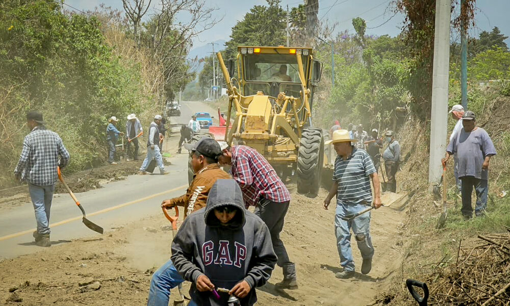 Faena comunitaria en Tochimilco con maquinaria y ciudadanos limpiando cunetas en la entrada principal del municipio