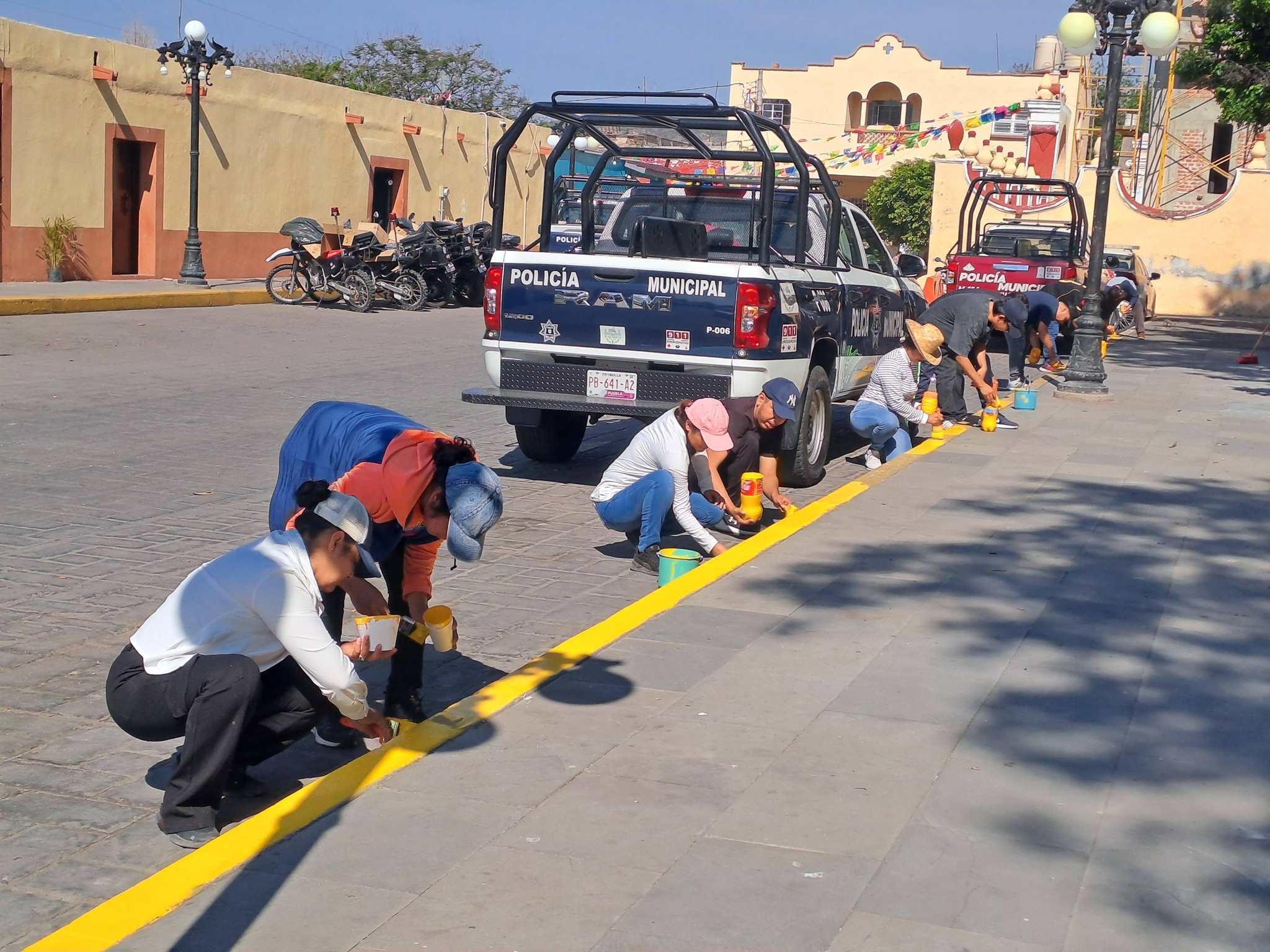 Trabajadores del Ayuntamiento de Huaquechula pintan guarniciones durante jornada de faena en el zócalo municipal