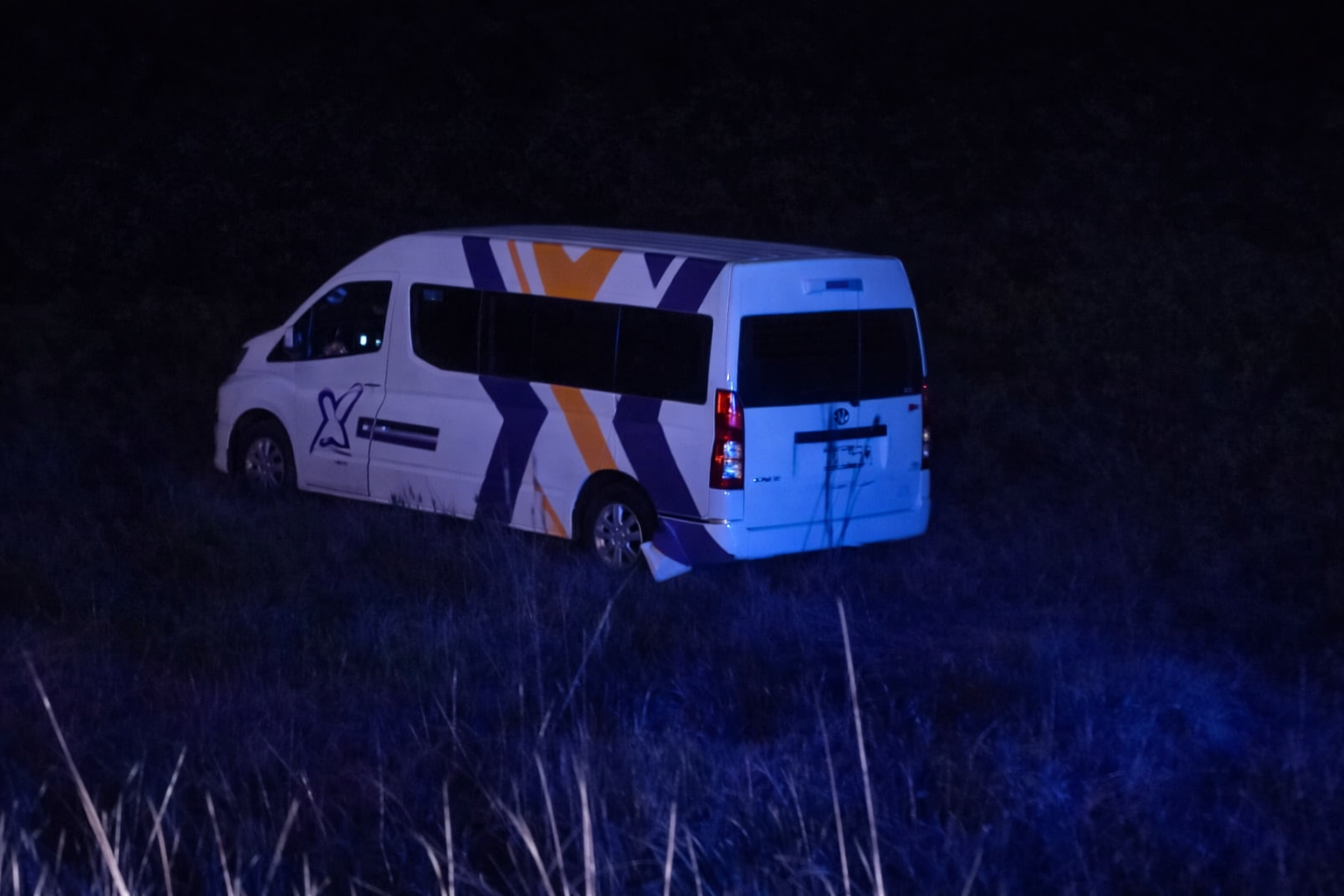 Combi de transporte público fuera de la carretera en zona de matorrales durante accidente nocturno en Puebla