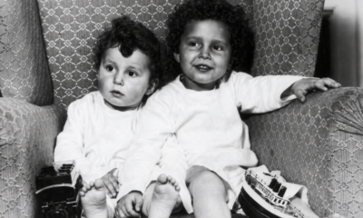 Fotografía en blanco y negro de dos niños sobrevivientes del Titanic sentados en un sillón con juguetes.
