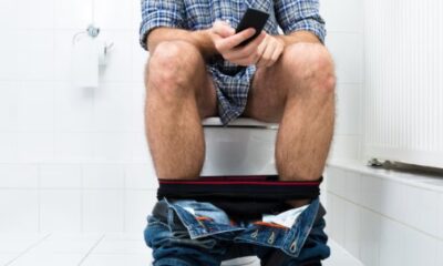 Persona usando celular mientras está sentada en el baño, relacionado con hábitos de salud