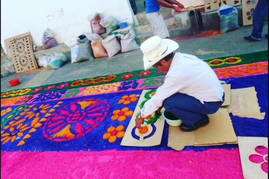 Persona elaborando alfombra de aserrín colorida en Atlixco durante Semana Santa