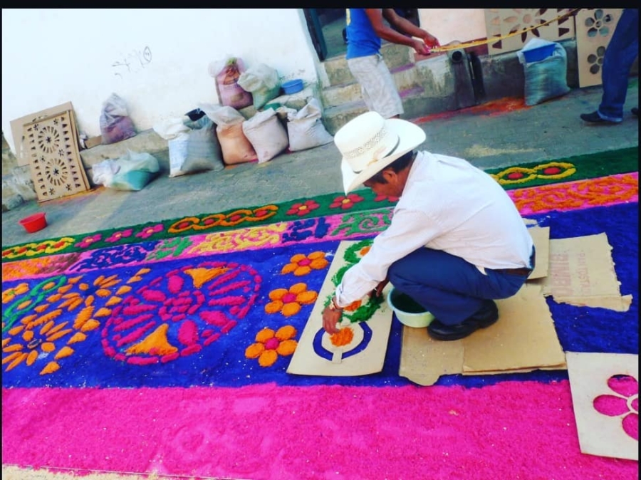 Persona elaborando alfombra de aserrín colorida en Atlixco durante Semana Santa